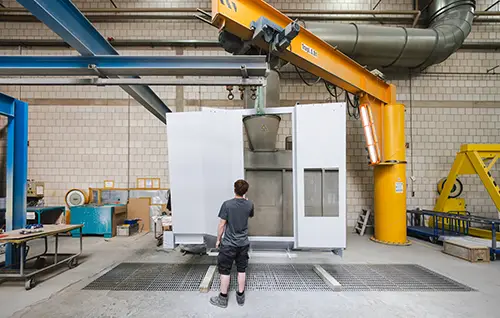 Kran hebt Bauteil in industrielle Anlage in der Fertigungshalle
