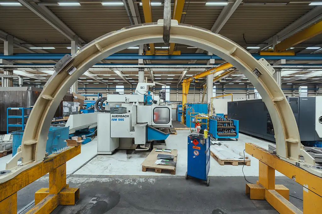 Blick durch einen großen Metallbogen auf eine Fräsmaschine in der Werkshalle